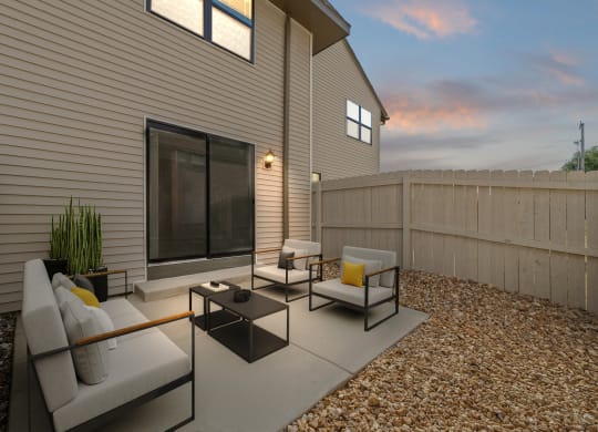 a patio with couches and chairs in front of a house