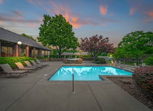 A swimming pool surrounded by lounge chairs and trees.