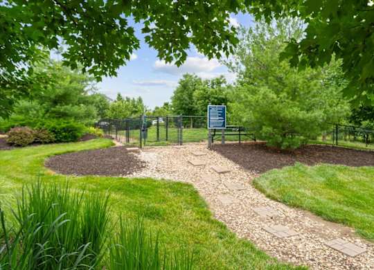 A sign is in a fenced area with a gravel path leading to it.