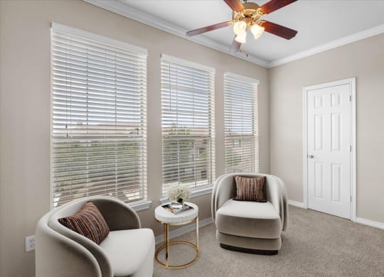 a living room with three windows and a ceiling fan at The Clairborne Apartment Homes, Grand Prairie, TX