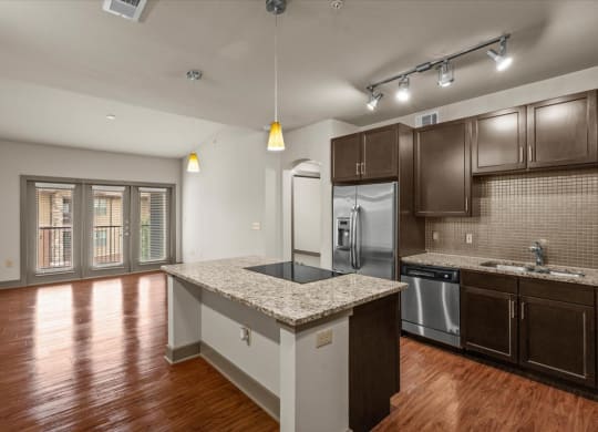 a kitchen with a large island with granite countertops and dark wood cabinets