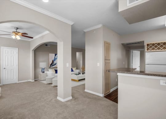 a living room and kitchen area with a ceiling fan at The Clairborne Apartment Homes, Grand Prairie