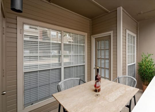 a patio with a table and chairs and a bottle of wine on the table at Creekview Apartment Homes, Dallas, Texas