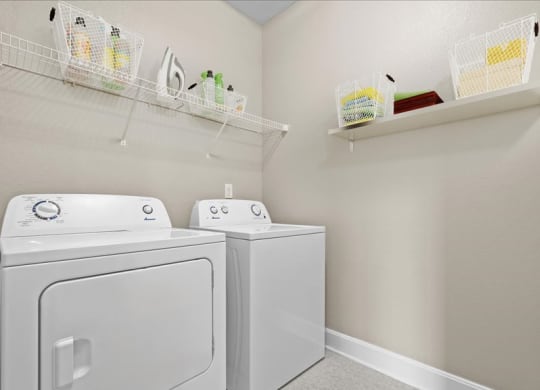a white laundry room with two washes and a dryer