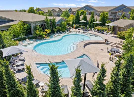 an aerial view of a resort style pool with chaise lounge chairs and umbrellas at Stonepost Crossing Apartments, Overland Park, Kansas