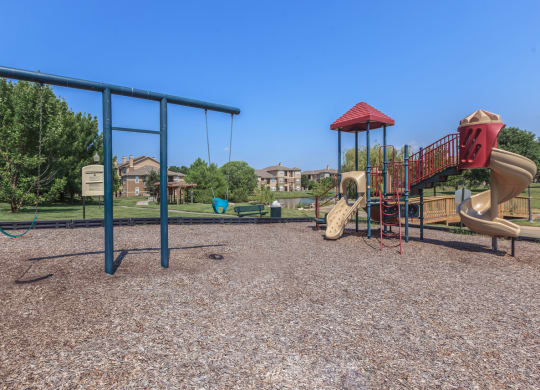 A playground with slides and swings at Stonepost Lakeside Apartments in Olathe, KS.