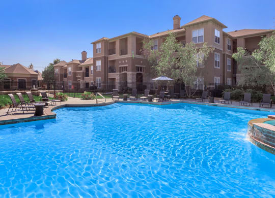 A beautiful swimming pool with lounge seating at Stonepost Lakeside Apartment Homes in Olathe, KS.
