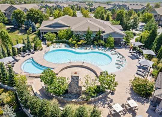 an aerial view of a resort style pool with chaise lounge chairs and umbrellas at Stonepost Crossing Apartments, Overland Park, Kansas
