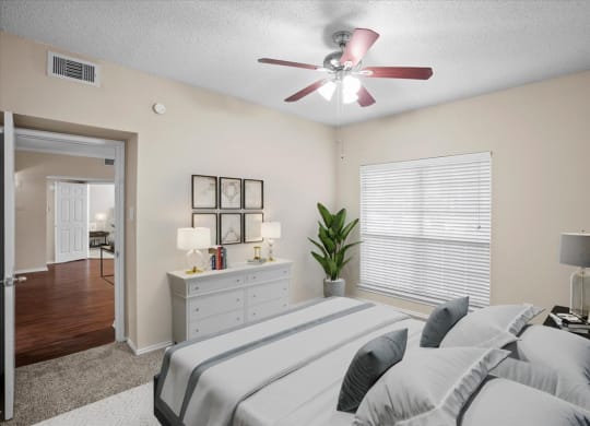 a bedroom with a large bed and a ceiling fan at Creekview Apartment Homes, Dallas