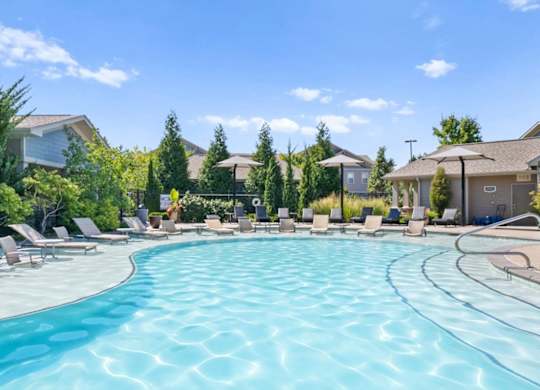 a swimming pool with chaise lounge chairs and umbrellas in front of a row of at Stonepost Crossing Apartments, Overland Park, Kansas