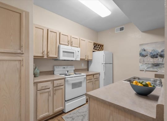 a kitchen with white appliances and wooden cabinets at The Clairborne Apartment Homes, Grand Prairie