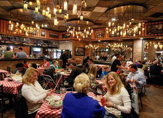A group of people are sitting at tables in a restaurant. at Residences at Prairiefire Apartment Homes, Overland Park