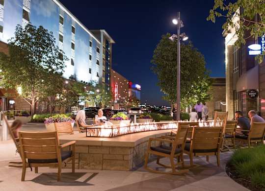 A group of people are sitting at a table outside at night. at Residences at Prairiefire Apartment Homes, Overland Park, KS, 66223