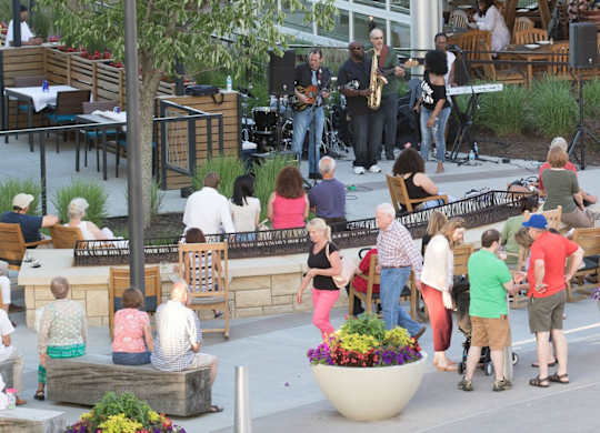A group of people are gathered around a stage with a band performing. at Residences at Prairiefire Apartment Homes, Kansas, 66223