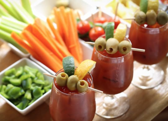Three glasses of a red beverage with olives and lemon slices on top. at Residences at Prairiefire Apartment Homes, Kansas