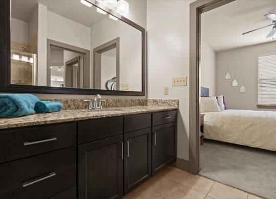 a bathroom with dark cabinets and a large mirror
