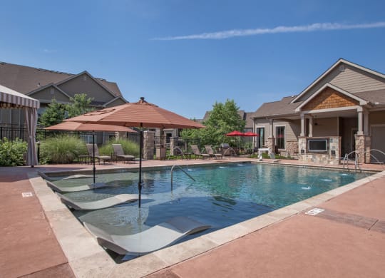 A saltwater outdoor swimming pool with shaded lounge seating, an outdoor TV, and a cabana.