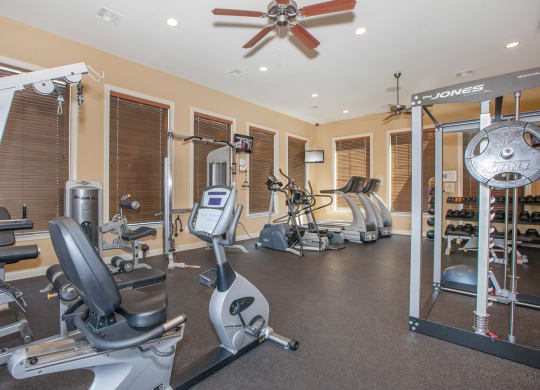 A fitness center with treadmills and strength training machines with a ceiling fan at Stonepost Ranch Apartments in Overland Park.