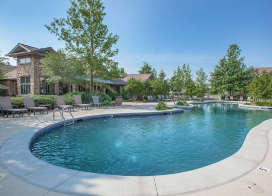 A beautiful clean lagoon pool with lush landscaping and lounge chair seating.
