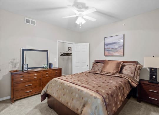 a bedroom with a bed and dresser at The Clairborne Apartment Homes, Grand Prairie