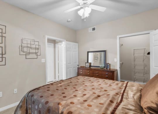 a bedroom with a bed and a ceiling fan at The Clairborne Apartment Homes, Grand Prairie, Texas