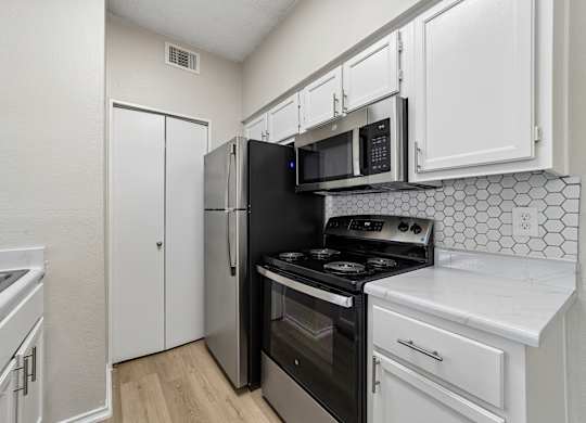 A kitchen with black appliances and white cabinets.