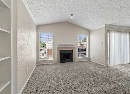 A spacious living room with a fireplace and large windows.