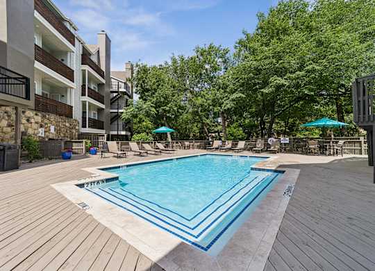 A pool surrounded by wooden decking and trees.