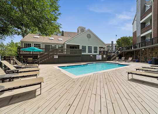 A wooden deck with a pool and lounge chairs.