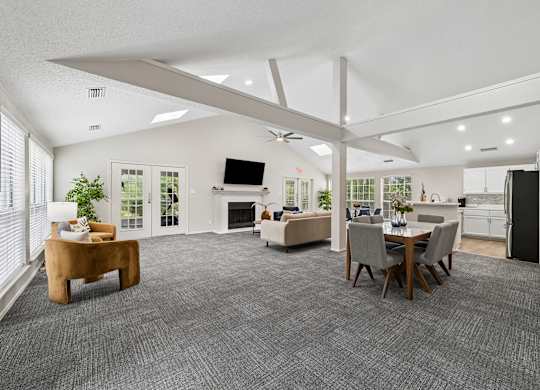 A spacious living room with a grey carpet and a television on the wall.