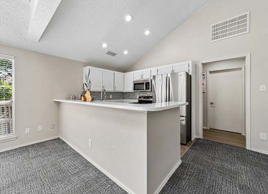 A kitchen with a white counter and a window with blinds.