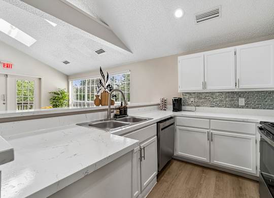 A kitchen with white cabinets and a marble countertop.