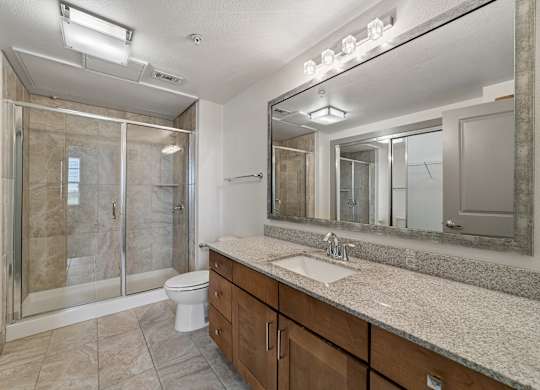 A bathroom with a sink, mirror, and shower.
