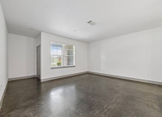 Empty room with a window and concrete floor.
