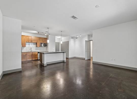 A large empty room with a kitchen area in the background.