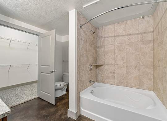 A bathroom with a white tub and beige tiles.