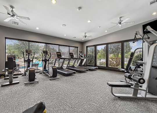 A spacious gym with various exercise equipment and a ceiling fan.