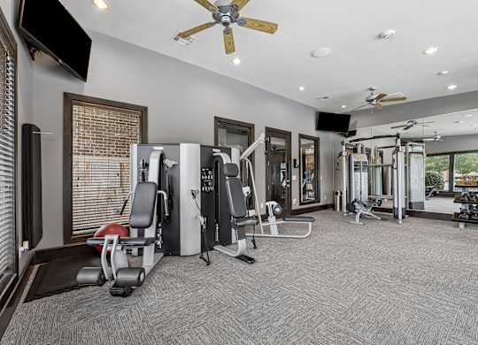 A spacious gym with a variety of equipment including treadmills, weights, and a television.