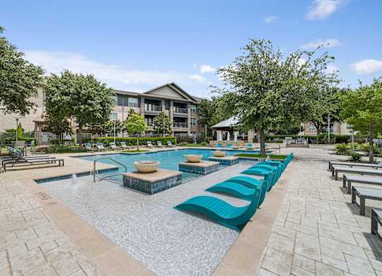 A large outdoor swimming pool with loungers and a building in the background.