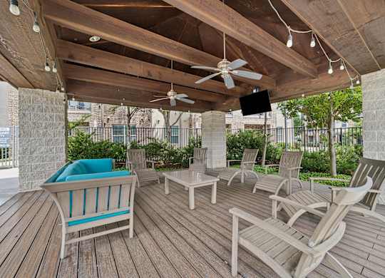A wooden deck with chairs and a fan.