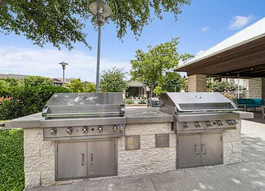 A stone outdoor kitchen with a grill and oven.