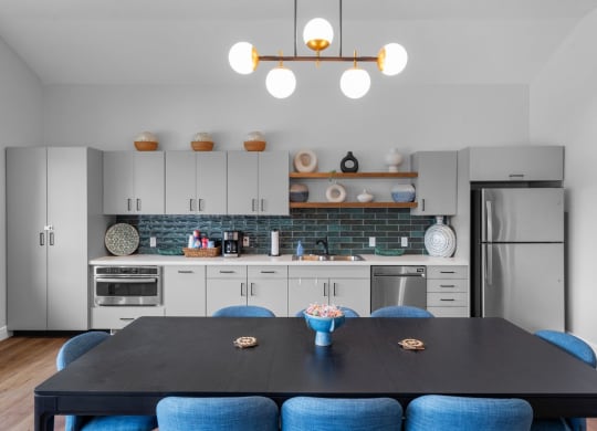 a kitchen with white cabinets and a table with blue chairs