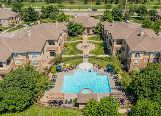 An aerial view of a swimming pool and courtyard surrounded by apartment buildings.