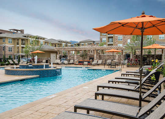 A pool area with sun loungers and umbrellas. at Residences at Prairiefire Apartment Homes, Overland Park, KS