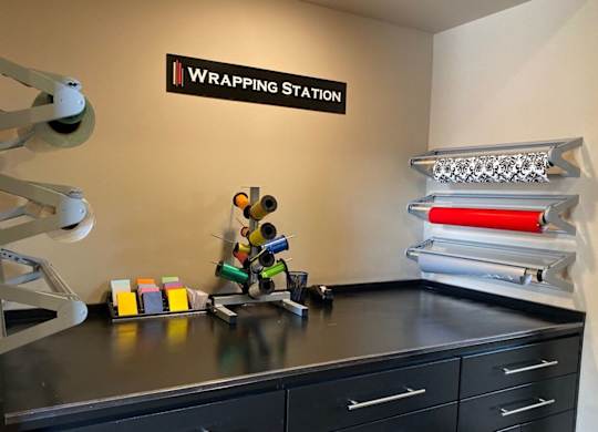A black countertop with a variety of wrapping paper and a sign  at Residences at Prairiefire Apartment Homes, Overland Park, KS