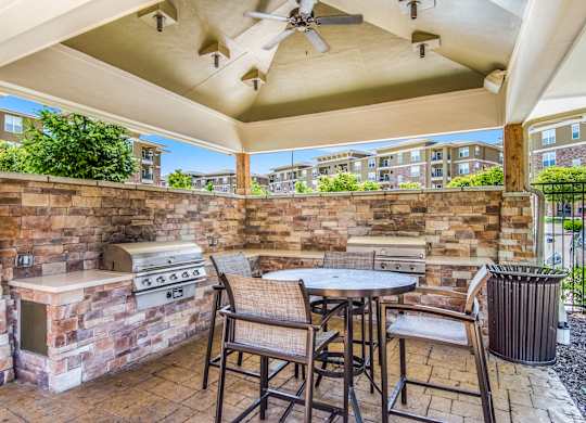 A patio with a table, chairs, and a grill. at Residences at Prairiefire Apartment Homes, Kansas