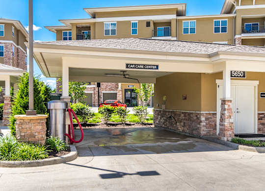 A car care center is located in a building with a stone pillar and a red hose. at Residences at Prairiefire Apartment Homes, Overland Park, 66223