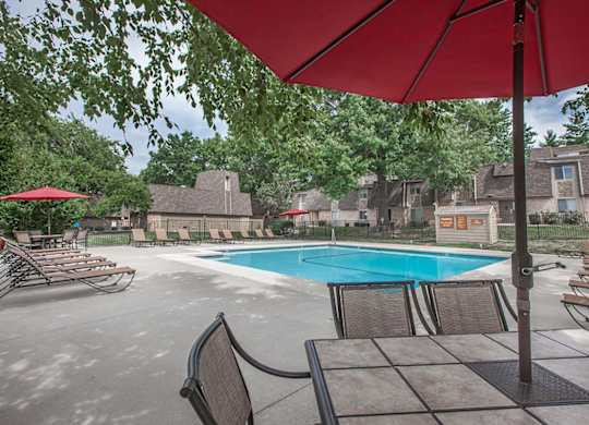 An outdoor dining area with umbrella shade by the outdoor pool at Preston Court.