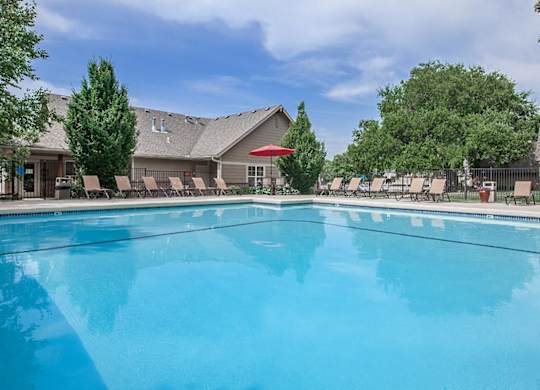 A sparkling outdoor swimming pool with landscaping and lounge chairs.