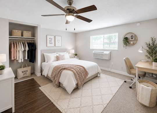 A bedroom with a bed, desk, and a ceiling fan.
